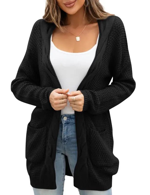 Black chunky cable knit women cardigan sweater with pockets over a white tank and jeans