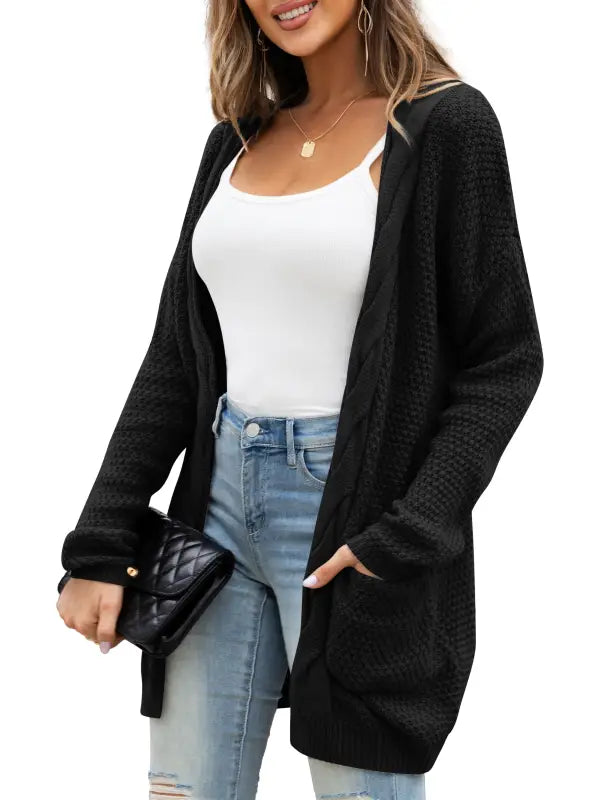 Black chunky cable knit cardigan sweater with pockets over white tank top and distressed jeans